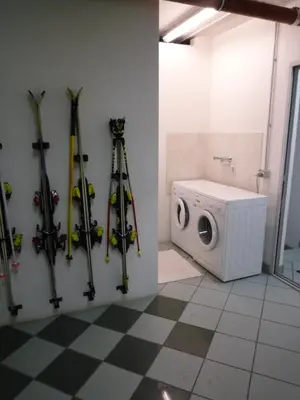 a bunch of skis hanging on a wall next to a washing machine at Residence Le Rose in Pozza di Fassa