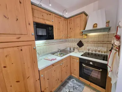 a kitchen with wooden cabinets and a sink and a stove at Residence Le Rose in Pozza di Fassa