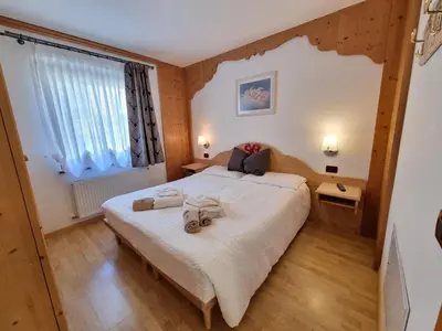 a bedroom with a large bed with two towels on it at Residence Le Rose in Pozza di Fassa