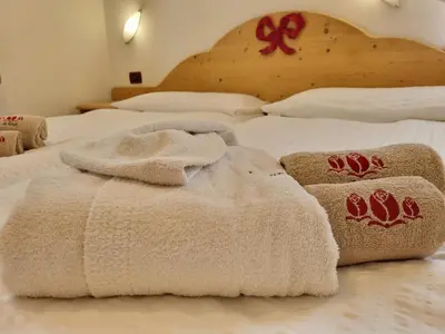 two white towels sitting on top of two beds at Residence Le Rose in Pozza di Fassa