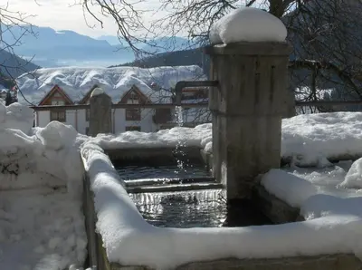 a stone water fountain in a snow covered yard at B&B Affittacamere Larix in Rumo