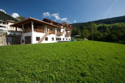 a house on a hill with a green field at B&B Affittacamere Larix in Rumo