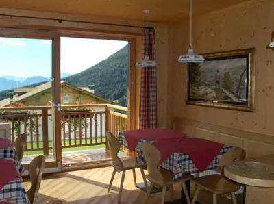 a room with a table and chairs and a balcony at B&B Affittacamere Larix in Rumo