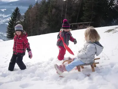 three children playing in the snow on a sled at Kaserhof wandern- Alleinlage - ruhig- top Aussicht in Bressanone