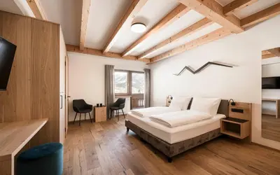 a bedroom with a bed in a room with wooden ceilings at Hotel Lahnerhof in Vipiteno