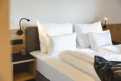 a white bed with white pillows on top of it at Hotel Lahnerhof in Vipiteno