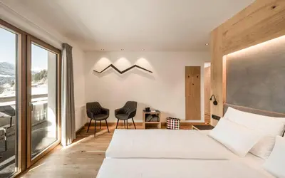a bedroom with a large bed and two chairs at Hotel Lahnerhof in Vipiteno