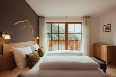 a bedroom with two beds and a large window at Refugium LaFlu Apartments in Corvara in Badia