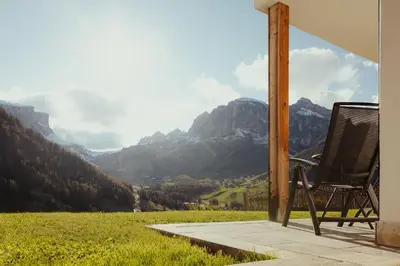 a chair on a porch with a view of mountains at Refugium LaFlu Apartments in Corvara in Badia