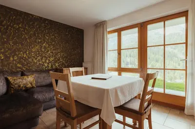 a dining room with a table and chairs and a couch at Refugium LaFlu Apartments in Corvara in Badia