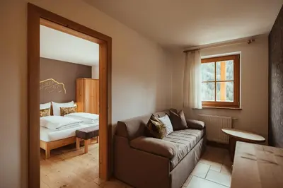 a living room with a couch and a bed at Refugium LaFlu Apartments in Corvara in Badia
