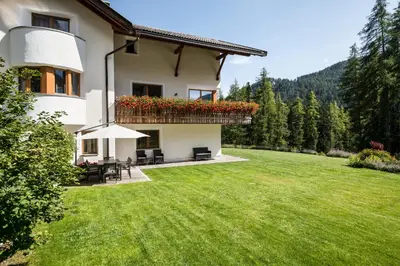 a house with a green yard with chairs and tables at Residence Floralp in Colfosco