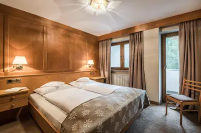 a bedroom with a large bed and a chair at Residence Floralp in Colfosco