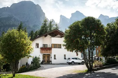 a white house with mountains in the background at Residence Floralp in Colfosco