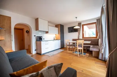 a kitchen and a living room with a couch and a table at Ausservogelweiderhof in Ponte Gardena