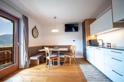 a kitchen with a table and chairs and a window at Ausservogelweiderhof in Ponte Gardena