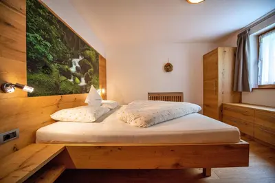 a bedroom with a bed with a large painting on the wall at Ausservogelweiderhof in Ponte Gardena
