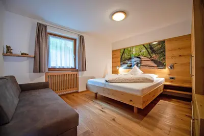 a bedroom with a bed and a couch in a room at Ausservogelweiderhof in Ponte Gardena
