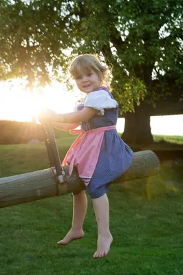 a little girl in a dress sitting on a tree limb at Dosserhof in Fiè