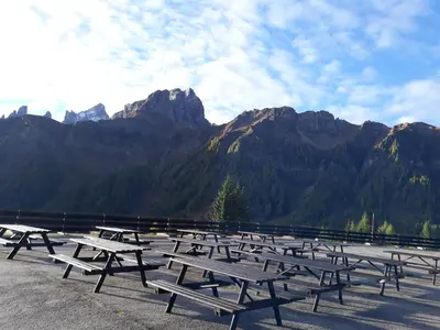 a row of picnic tables in front of mountains at Casa Mowgli - Residence Sussy in Falcade