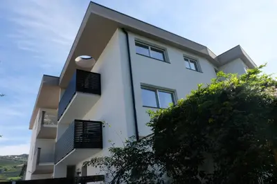 a white building with black windows and a tree at Apartment Le rose di Marianne - ovest in Varna