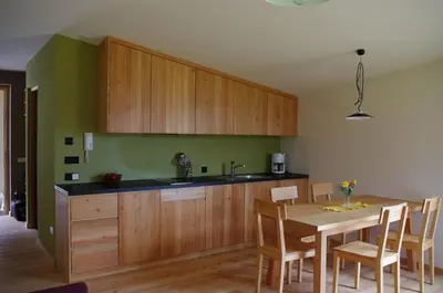 a kitchen with wooden cabinets and a table with chairs at Biobauernhof St. Quirinus in Caldaro