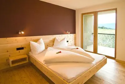 a bedroom with a large white bed with a window at Biobauernhof St. Quirinus in Caldaro