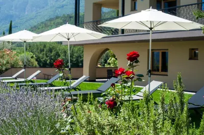 a group of tables with umbrellas and red flowers at Biobauernhof St. Quirinus in Caldaro