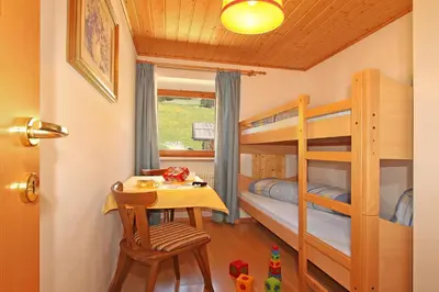 a bedroom with bunk beds and a table and a desk at Schmözlhof in Tesido