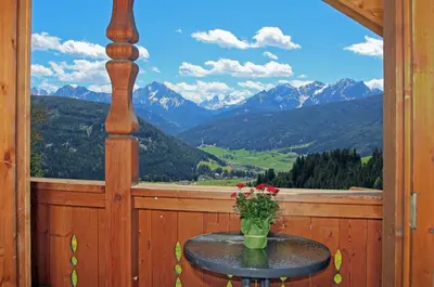 a table on a balcony with a view of mountains at Schmözlhof in Tesido