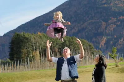 a man with a little girl jumping in the air at Kessler's Mountain Lodge in Naz-Sciaves
