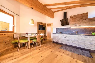 a kitchen with wooden floors and a table and chairs at Untermathonhof Vöran - Ferienwohnungen - Urlaub am Bauernhof in Südtirol mit hofeigenem Frühstück in Verano