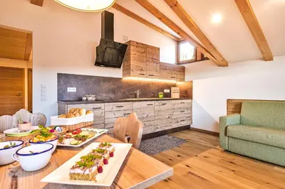 a kitchen and living room with a table with food at Untermathonhof Vöran - Ferienwohnungen - Urlaub am Bauernhof in Südtirol mit hofeigenem Frühstück in Verano