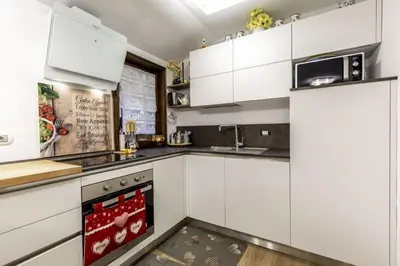 a kitchen with white cabinets and a stove top oven at Des Alpes 2 in Canazei