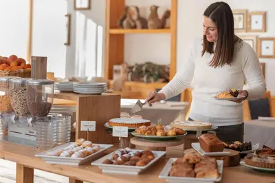 a woman standing in front of a table with food at Phi Hotel Bellamonte in Predazzo