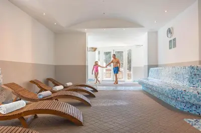a man and a little girl in a room with chairs at Phi Hotel Bellamonte in Predazzo