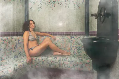 a woman sitting on a couch in a bathroom at Phi Hotel Bellamonte in Predazzo