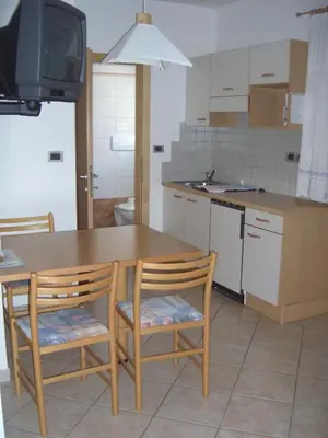a kitchen with a wooden table and two chairs at Ferienwohnung im Haus Texel III in Parcines