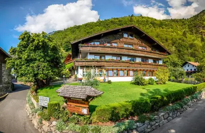 a large wooden house with a green yard at Garni-Hotel Farmerhof in Parcines