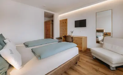 a bedroom with a bed and a chair at Garni-Hotel Farmerhof in Parcines
