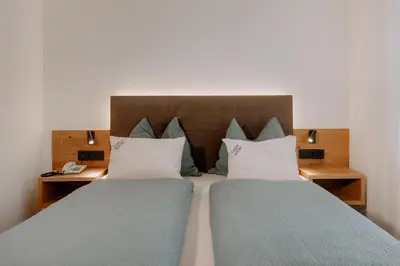 a bedroom with two beds with blue and white pillows at Garni-Hotel Farmerhof in Parcines