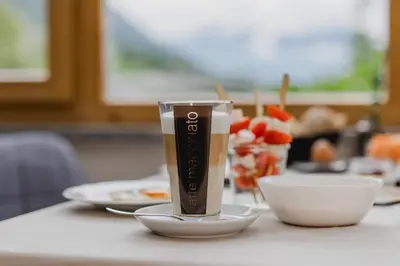 a glass of coffee sitting on a table with a bowl at Garni-Hotel Farmerhof in Parcines