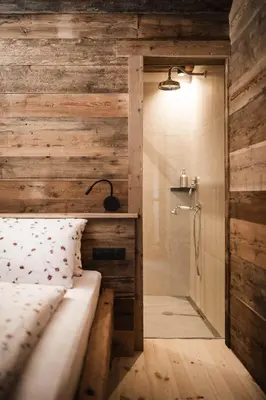 a bedroom with a wooden wall and a shower at Huberhof in Fiè