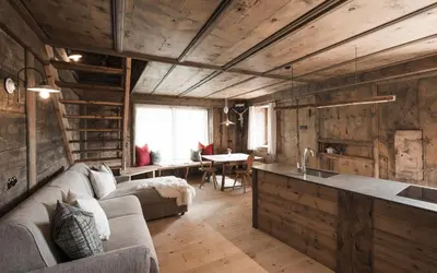 a living room with a couch and a kitchen and a table at Huberhof in Fiè