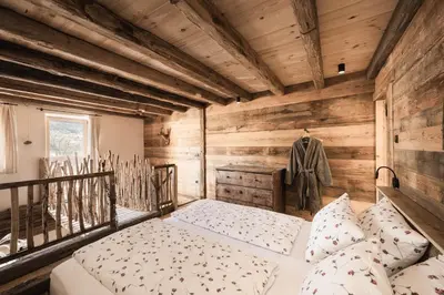 a bedroom with a bed in a wooden room at Huberhof in Fiè