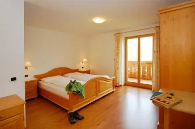 a bedroom with a wooden bed and a balcony at Urthalerhof in Castelrotto