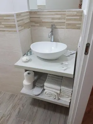 a bathroom with a white sink and towels on a shelf at Giuchry Apartment in Merano