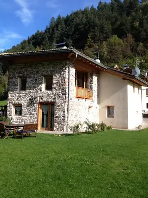 a stone house with a picnic table in front of it at Maso Toneto in Castello di Fiemme