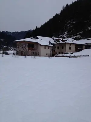 a snow covered field with a building in the background at Maso Toneto in Castello di Fiemme
