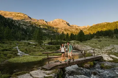 a man and woman walking across a bridge over a river at Hotel Elisabeth in Chienes